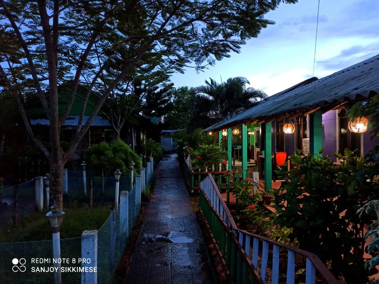 Tajpur Retreat campus walkway at dusk with lantern lights